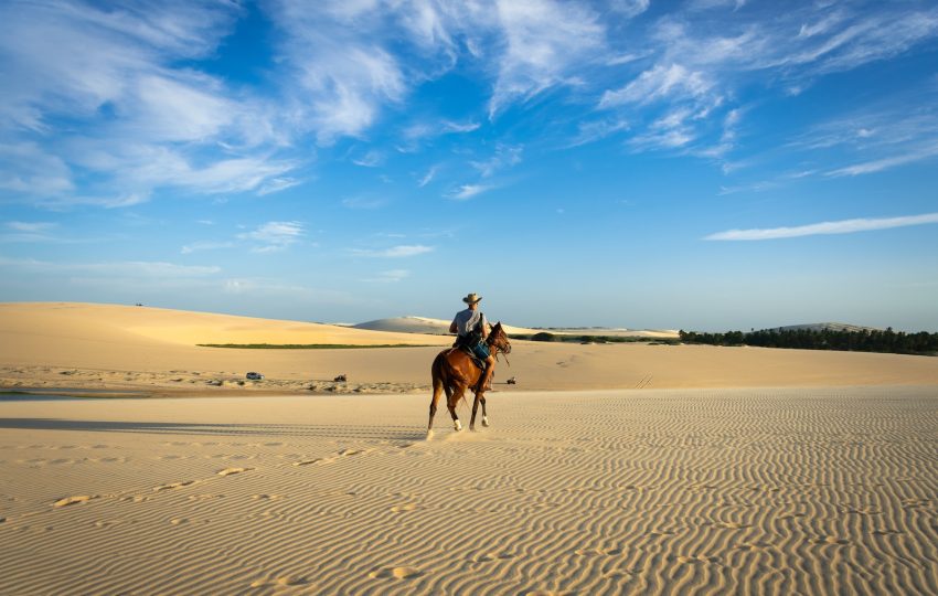 man riding on horse at middle of desert